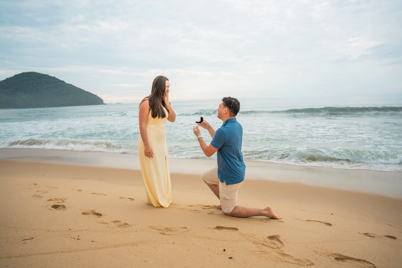 Diogo de joelho na areia, pedindo Mariana em noivado